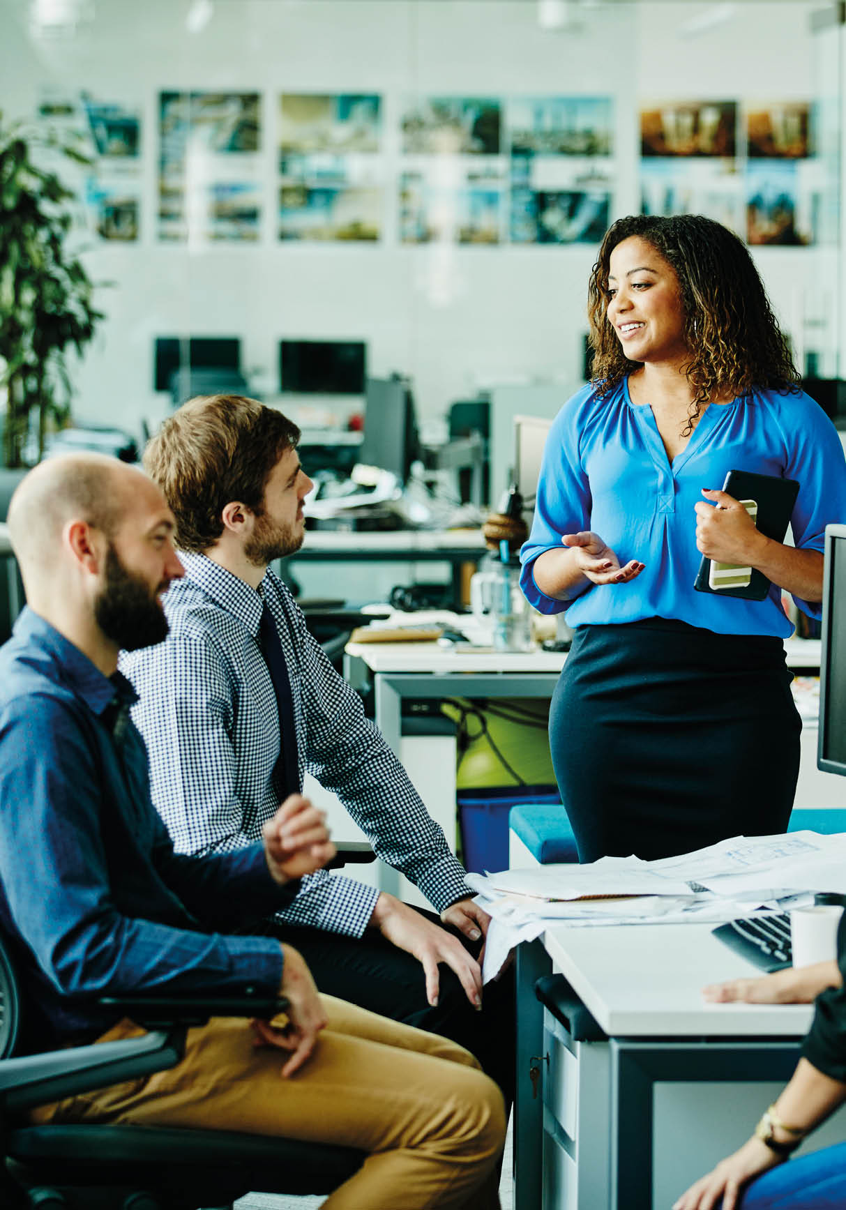 Businesswoman leading informal meeting with colleagues at office workstation